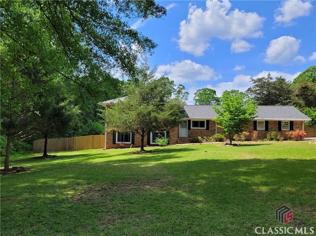 view of front of home featuring brick siding, fence, and a front yard
