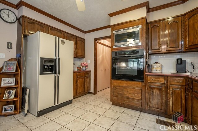 749 Diamond Hill Colbert Rd, Colbert, GA 30628 - kitchen with white refrigerator with ice dispenser, decorative backsplash, stainless steel microwave, black oven, and crown molding