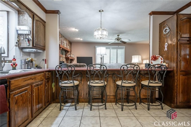 749 Diamond Hill Colbert Rd, Colbert, GA 30628 - kitchen featuring light tile patterned floors, ornamental molding, ceiling fan with notable chandelier, and a kitchen bar