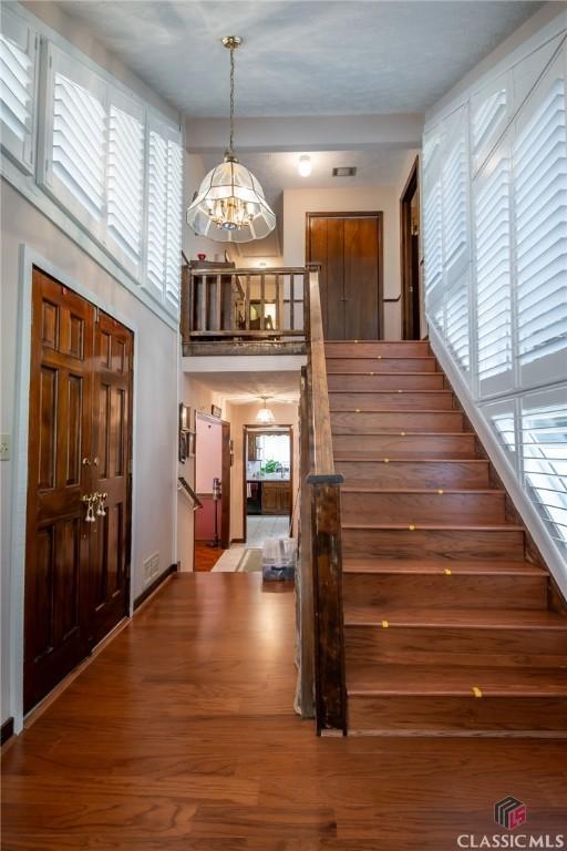 749 Diamond Hill Colbert Rd, Colbert, GA 30628 - stairs featuring a chandelier, wood finished floors, and a high ceiling