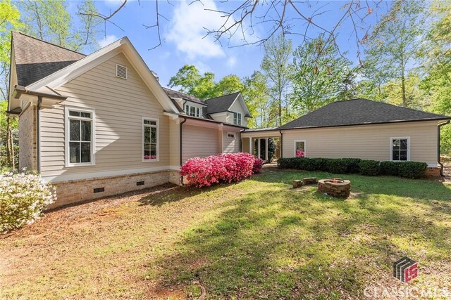 147 Rapids Dr, Bogart, GA 30622 - view of home's exterior with a fire pit, a shingled roof, a yard, and crawl space
