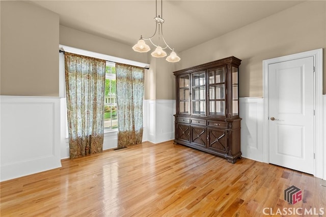 147 Rapids Dr, Bogart, GA 30622 - unfurnished dining area featuring a wainscoted wall, a chandelier, a decorative wall, and light wood-type flooring