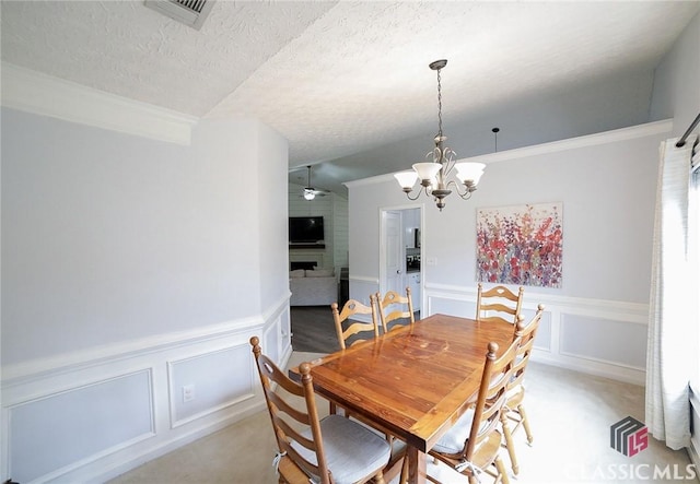 dining area featuring visible vents, a wainscoted wall, a textured ceiling, and a decorative wall