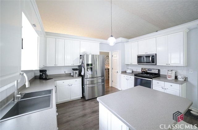 kitchen with white cabinetry, a sink, appliances with stainless steel finishes, dark wood finished floors, and hanging light fixtures