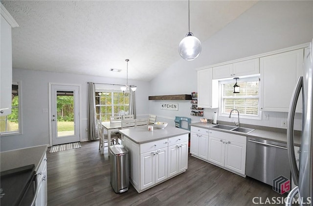 kitchen featuring stainless steel appliances, vaulted ceiling, white cabinets, dark wood-style flooring, and a sink