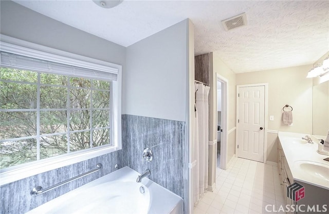 full bathroom featuring a sink, visible vents, double vanity, a garden tub, and tile patterned flooring