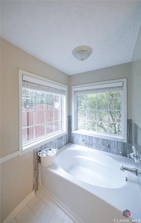 full bathroom featuring a textured ceiling, a bath, and tile patterned flooring