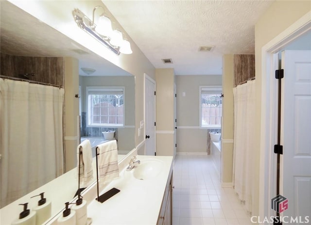 bathroom with a textured ceiling, visible vents, a garden tub, and tile patterned flooring