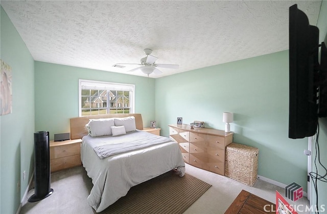 bedroom with a ceiling fan, visible vents, baseboards, a textured ceiling, and carpet floors