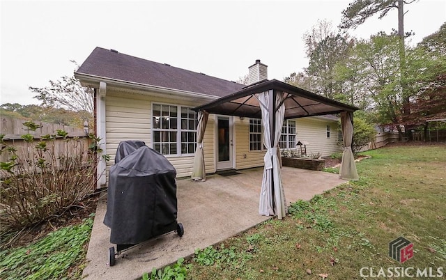 back of property featuring a patio area, a lawn, a chimney, a gazebo, and fence