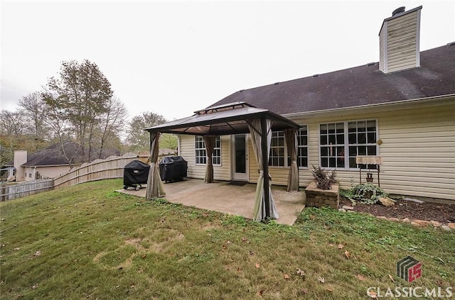 rear view of property with a patio, a chimney, a gazebo, fence, and a yard