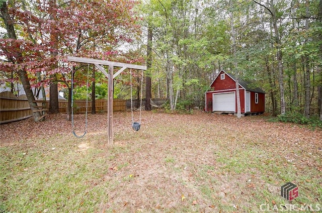 view of yard featuring an outbuilding, a detached garage, a shed, and fence