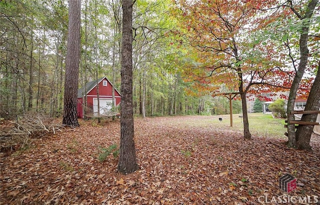 view of yard with a detached garage, an outdoor structure, and a view of trees