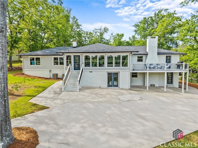 back of property featuring a deck, a patio, roof with shingles, a chimney, and central AC unit