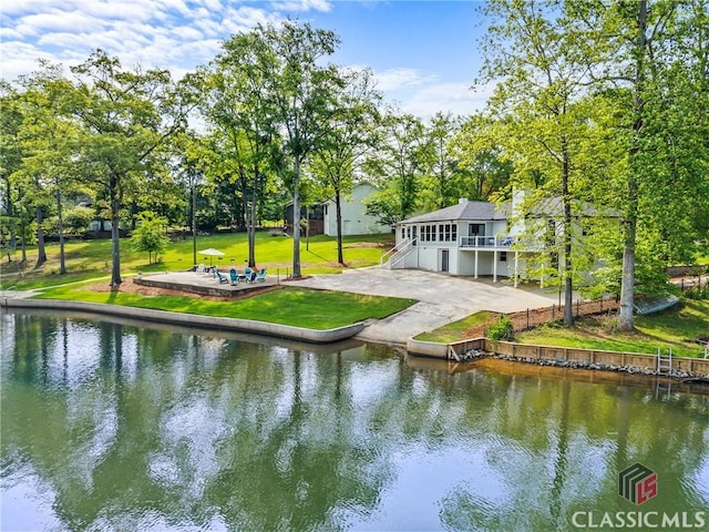 exterior space with a lawn, a patio, fence, and a deck with water view