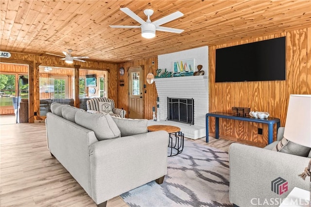 living area featuring wooden ceiling, ceiling fan, a fireplace, and wood walls