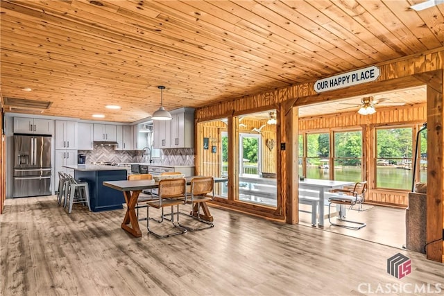 dining space featuring a ceiling fan, wood walls, wood ceiling, and wood finished floors