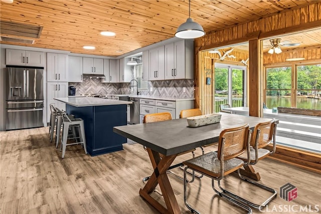 kitchen with light countertops, appliances with stainless steel finishes, wooden ceiling, and a kitchen island
