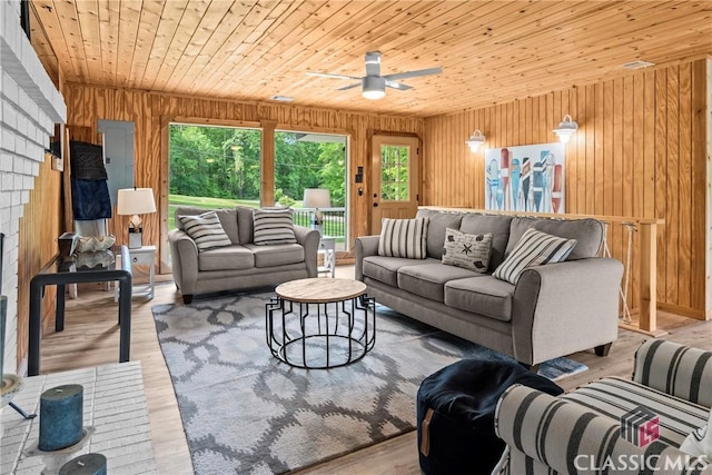 living room with a ceiling fan, wood walls, a healthy amount of sunlight, and wood finished floors