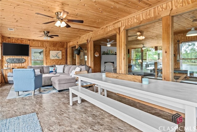 living room with wooden walls, wooden ceiling, plenty of natural light, and a fireplace