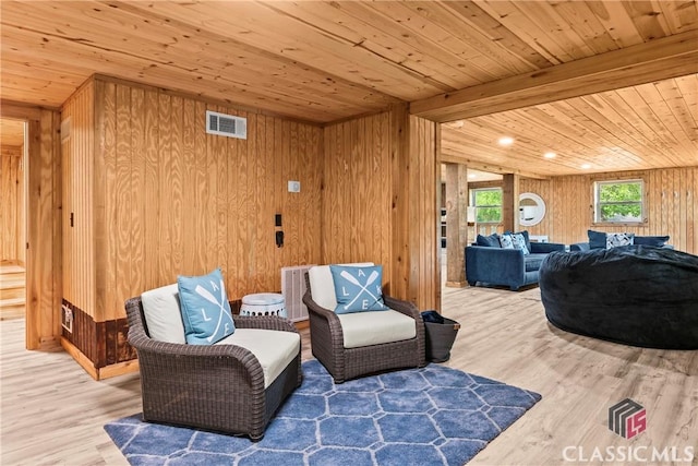 sitting room with wooden walls, wood ceiling, visible vents, and wood finished floors