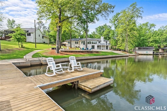 view of dock with a lawn and a water view