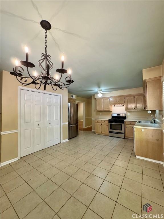 kitchen with light countertops, light tile patterned floors, a sink, a chandelier, and stainless steel appliances