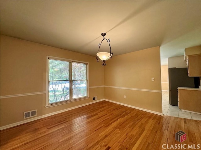 unfurnished dining area with baseboards, visible vents, and light wood-type flooring