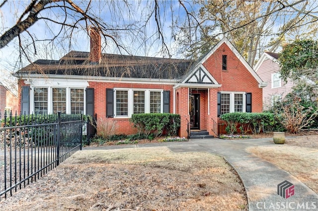 view of front facade with fence, a chimney, and brick siding
