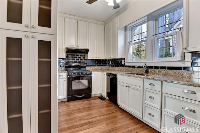 kitchen with under cabinet range hood, white cabinetry, a sink, and black appliances