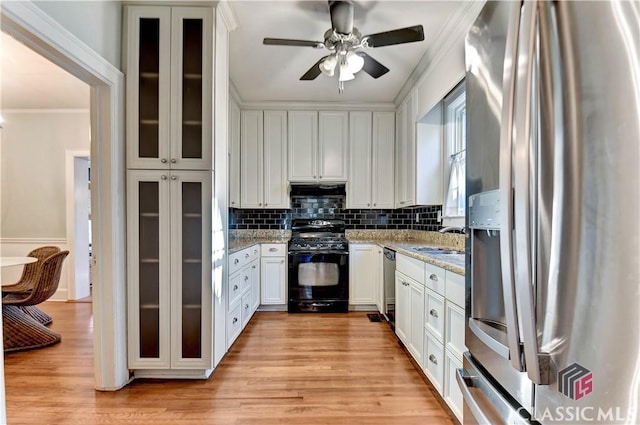 kitchen with stainless steel appliances, white cabinetry, and ornamental molding