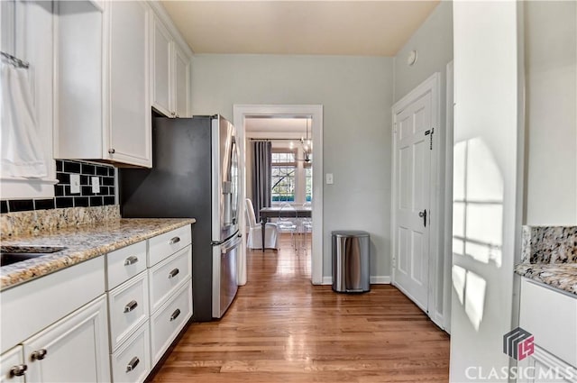 kitchen with decorative backsplash, light wood-type flooring, and white cabinets