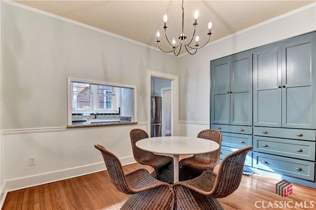 dining room featuring baseboards, ornamental molding, wood finished floors, and a notable chandelier
