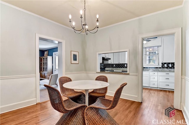 dining room featuring light wood-style floors, baseboards, ornamental molding, and a chandelier
