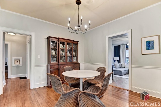 dining room with baseboards, a notable chandelier, ornamental molding, and light wood-type flooring