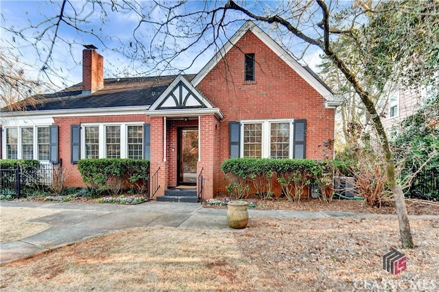tudor house featuring brick siding and a chimney