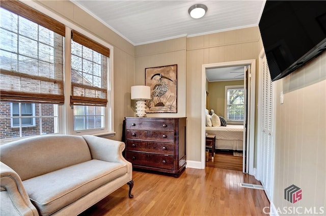 sitting room with ornamental molding and light wood-style flooring