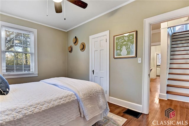 bedroom with baseboards, ornamental molding, and wood finished floors