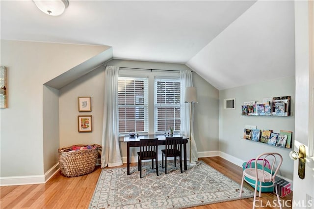 interior space featuring visible vents, baseboards, wood finished floors, and vaulted ceiling