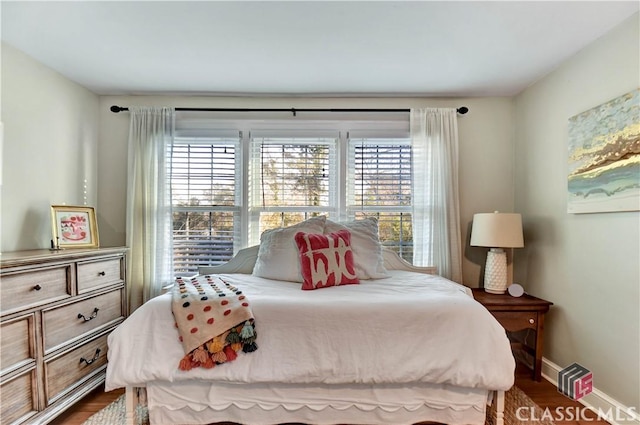 bedroom with baseboards, dark wood finished floors, and multiple windows