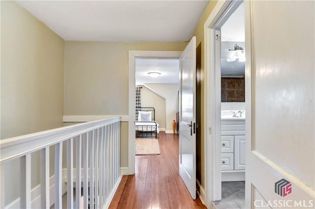 hall featuring a sink, baseboards, and wood finished floors