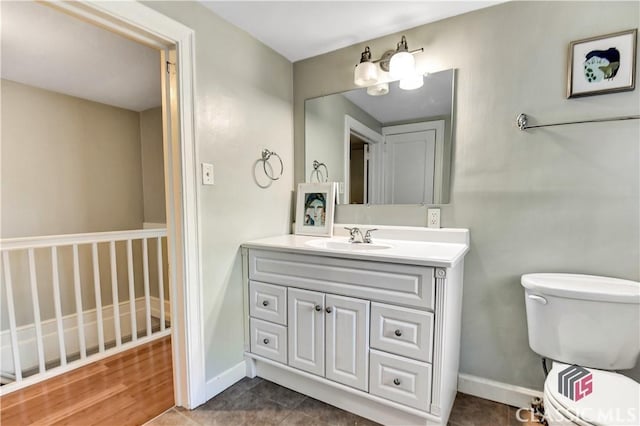 bathroom with toilet, baseboards, and vanity