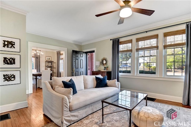 living room featuring crown molding, baseboards, wood finished floors, and ceiling fan with notable chandelier