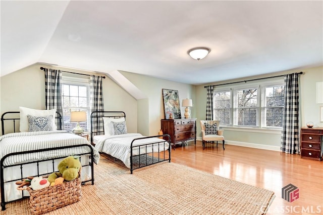 bedroom with baseboards, vaulted ceiling, and wood finished floors