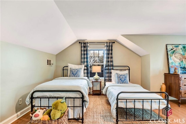 bedroom with baseboards, wood finished floors, and vaulted ceiling