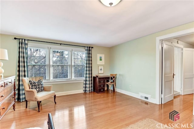 sitting room featuring baseboards, visible vents, and light wood-type flooring