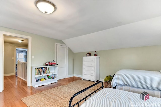 bedroom with baseboards, vaulted ceiling, and wood finished floors