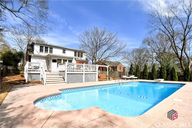 view of swimming pool with stairs, a wooden deck, a fenced in pool, a fenced backyard, and a patio area