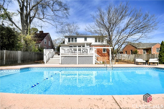 view of swimming pool with a fenced in pool, a wooden deck, and stairway