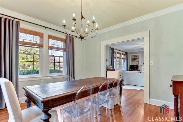 dining area featuring an inviting chandelier, baseboards, crown molding, and light wood finished floors